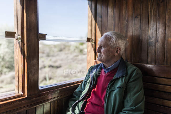 Attractive man and old man traveling in an old wooden train carriage looking out the window — Stock Photo