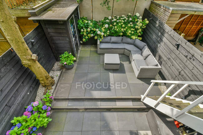 From above of backyard with staircase against sofa between table and blooming flowers in daytime — Stock Photo