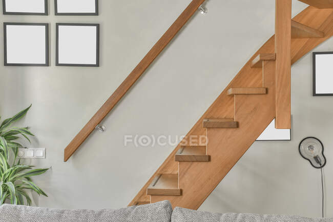 Intérieur de la pièce lumineuse avec escalier en bois et peintures avec des toiles vides dans un appartement moderne — Photo de stock