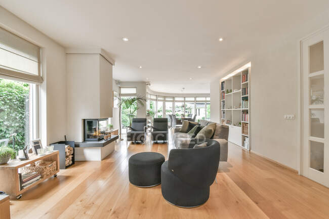 Habitación contemporánea interior con sillones y sofá con cojines decorativos contra chimenea en casa de luz - foto de stock