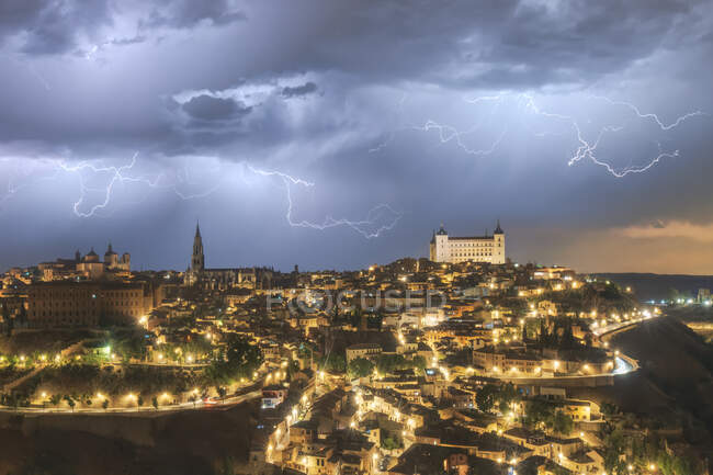 Paesaggio urbano con invecchiato famoso castello Alcazar di Toledo collocato in Spagna sotto il cielo nuvoloso di notte durante il temporale — Foto stock