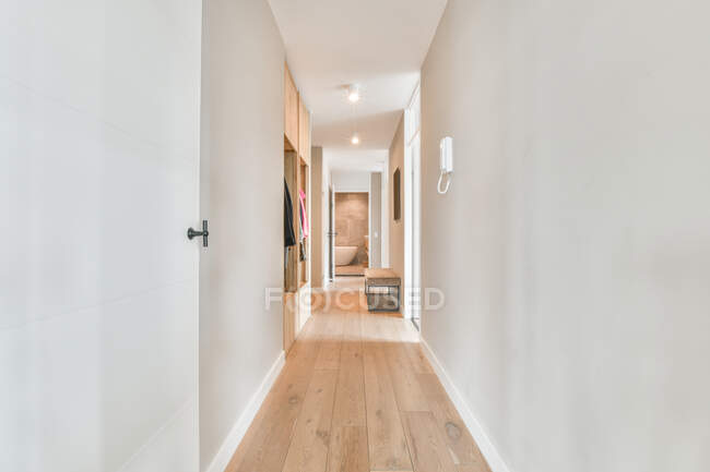 Пустой длинный коридор с белыми стенами и паркетом в современной квартире днем — стоковое фото