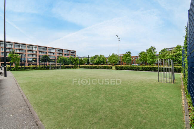 Soccer field against multistory building exteriors and lush green trees under cloudy sky in Amsterdam Netherlands — Stock Photo