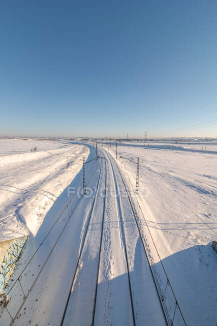 Vista do drone do trem na estrada de ferro no terreno nevado sob o céu claro azul — Fotografia de Stock