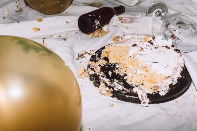 Смажений торт на день народження на крихкій брудній тканині біля повітряного скла з пляшками на вечірці. — стокове фото