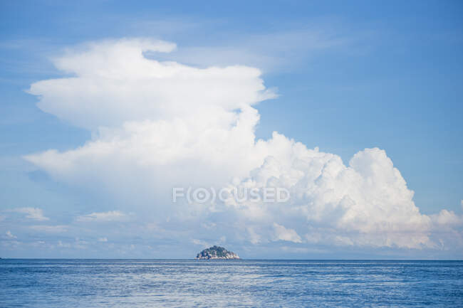 Пейзаж прозрачного синего волнистого моря с скалистым островом на горизонте под облаками в солнечный день в Малайзии — стоковое фото