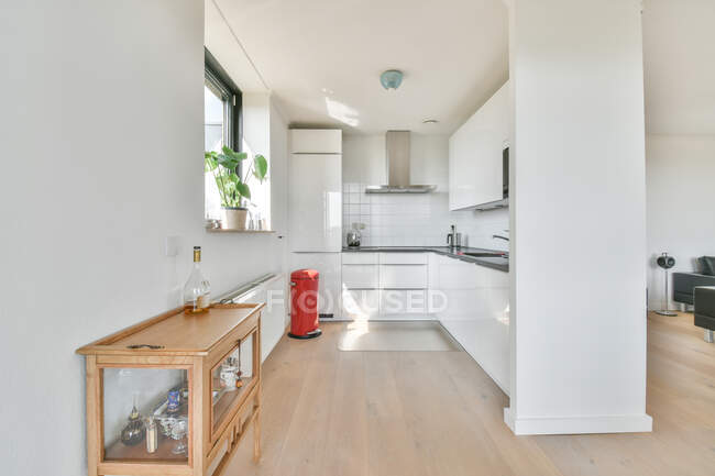 Interior de cozinha moderna com armários e cafeteira contra lata de lixo em casa à luz do sol — Fotografia de Stock