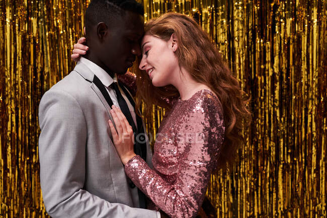 Вид збоку молодої романтичної багаторасової пари в стильному одязі, що приймається під час святкування Нового року — стокове фото