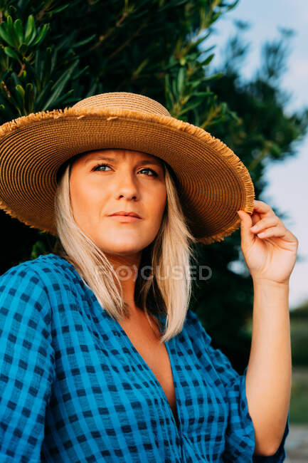 Schnodderige erwachsene Touristin mit Hut schaut weg vom Busch in Saint Jean de Luz Frankreich — Stockfoto