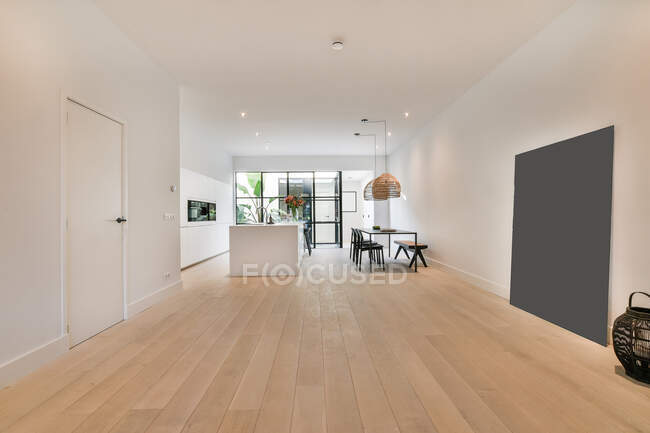 Cozinha contemporânea e sala de jantar interior minimalista com móveis em parquet entre porta e painel em casa — Fotografia de Stock
