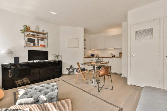 Interior do apartamento contemporâneo com sala de estar elegante e zona de cozinha leve à luz do dia — Fotografia de Stock
