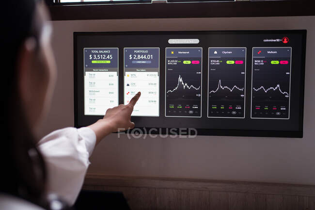 Crop anonymous female trader pointing at monitor with cryptocurrency and crypto wallet statistics — Stock Photo