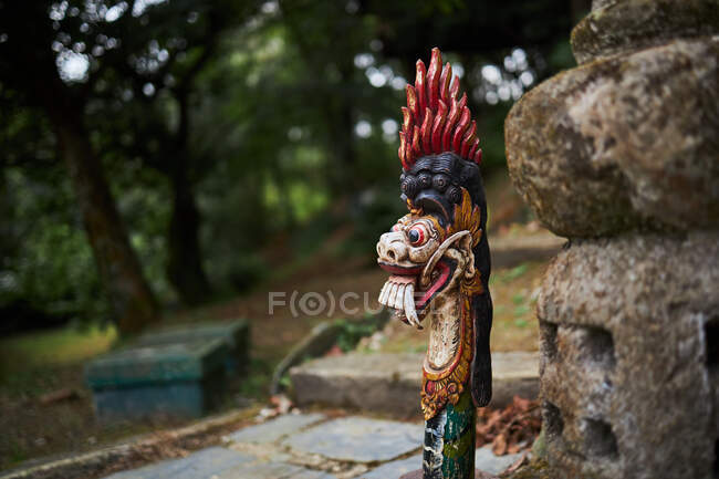Escultura tradicional balinesa de dragón con adorno contra la pared rugosa a la luz del día en Bali Indonesia - foto de stock