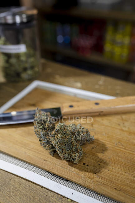 From above knife against dried hemp floral buds on chopping board in room — Stock Photo