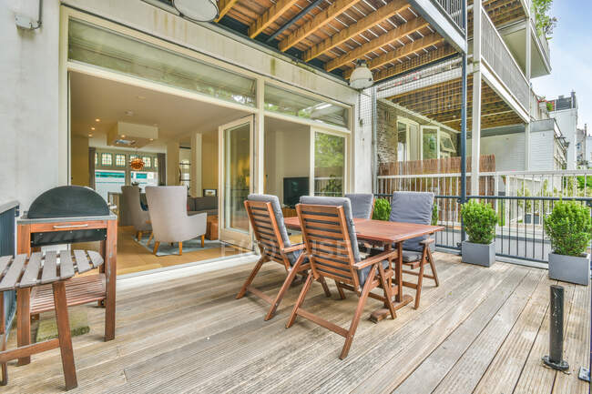 Table en bois et fauteuils confortables placés sur le balcon en bois de la maison moderne dans la campagne en été — Photo de stock