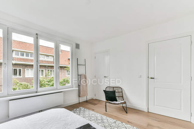 Bequemes Bett mit weißer Decke bedeckt auf Teppich in der Nähe des Fensters im stilvollen Schlafzimmer platziert — Stockfoto