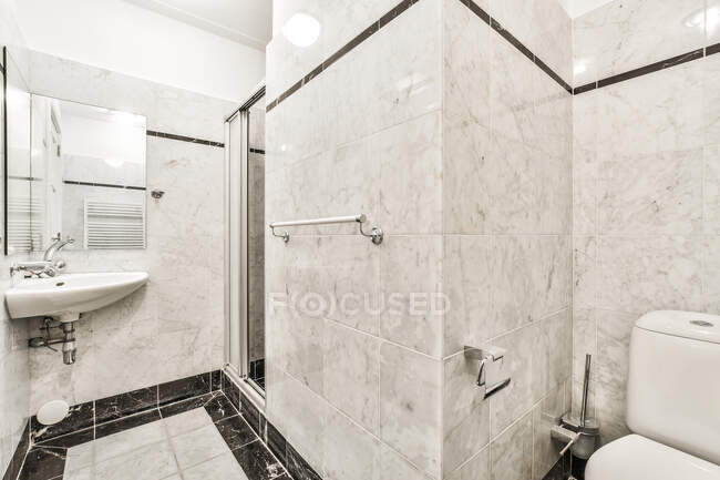 Інтер'єр сучасної світлої ванної кімнати з туалетом біля душової кабіни і раковиною під дзеркалом в сучасній квартирі — стокове фото