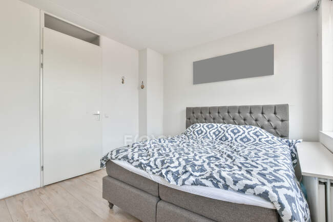 Interno della camera da letto luce con ampio letto confortevole con biancheria elegante durante il giorno — Foto stock