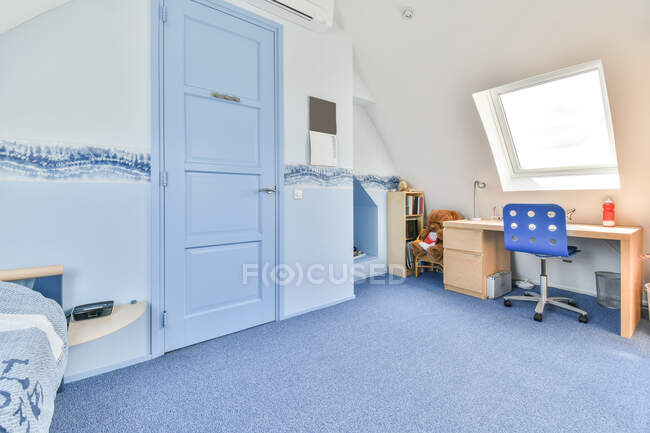 Interior do quarto contemporâneo com porta entre cama e mesa sob janela em casa com ornamento azul ondulado nas paredes — Fotografia de Stock