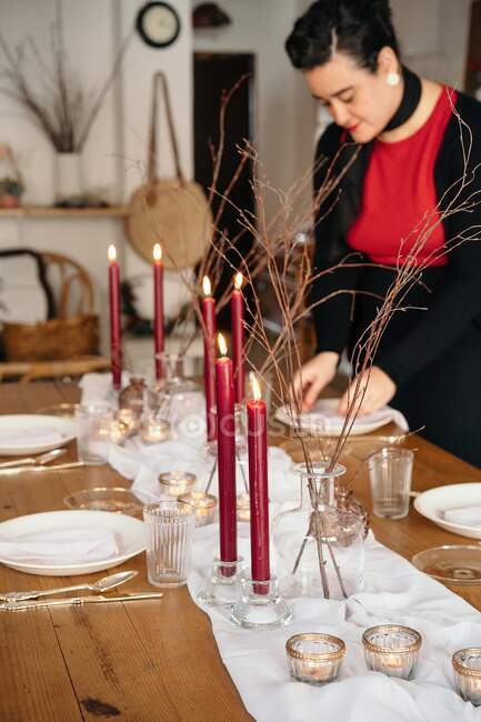 Calma giovane donna in abiti casual in piedi organizzare tavolo festivo in camera luce durante il giorno — Foto stock