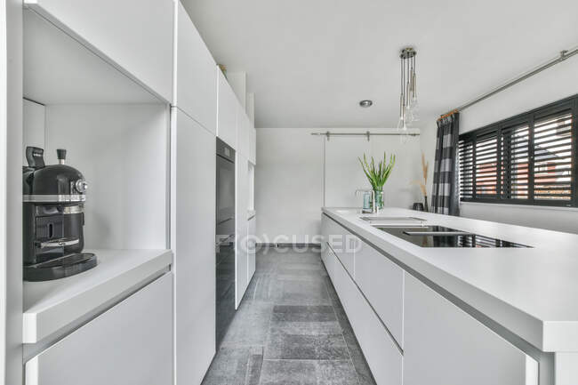 Light interior of kitchen with metal sink and built in appliances in modern house — Stock Photo