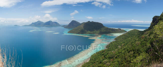 Amplo ângulo de paisagem marinha com água do mar azul-turquesa lavando colinas verdes florestadas nos trópicos da Malásia — Fotografia de Stock