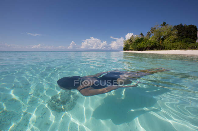Женщина-туристка в купальнике плавает под водой из кристально синего волнистого моря во время отдыха в Малайзии — стоковое фото