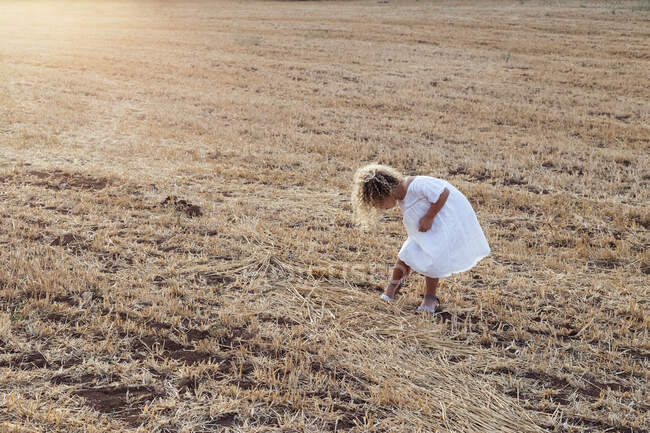 Little blonde girl alone in a field on a sunny day — Stock Photo