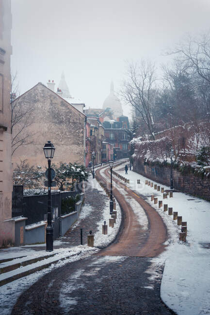 Empty narrow paved road in historic district of Paris with Sacre Coeur Basilica in mist in winter day — Stock Photo