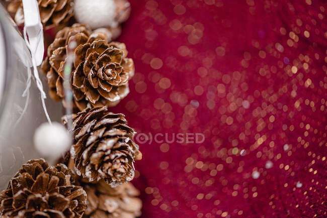 Свеча в стеклянном держателе украшена конусами и звездами, поставленными на стол для празднования Рождества — стоковое фото