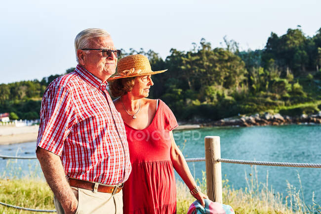 Senioren stehen dicht beieinander und schauen weg und genießen den Blick auf das Meer an einem sonnigen Tag — Stockfoto