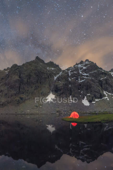 Scenic view of tent on lake shore against snowy mountain under cloudy sky in evening — Stock Photo