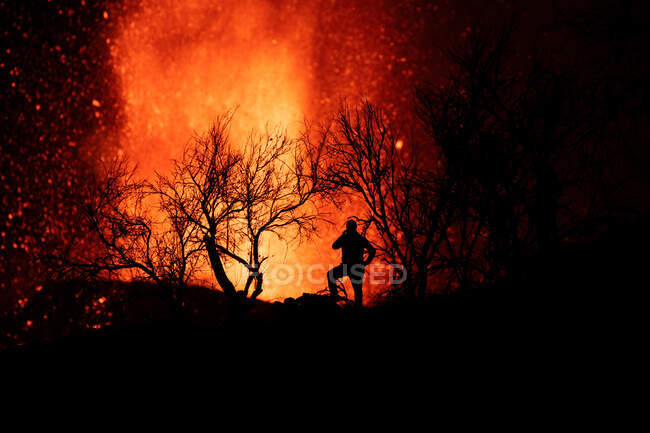 Human silhouette standing against exploding lava and magma pouring out of the crater. Cumbre Vieja volcanic eruption in La Palma Canary Islands, Spain, 2021 — Stock Photo