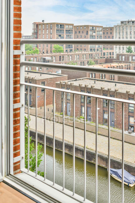 Vista através da janela do apartamento na rua da cidade com canal fluvial e edifícios residenciais em dia ensolarado — Fotografia de Stock