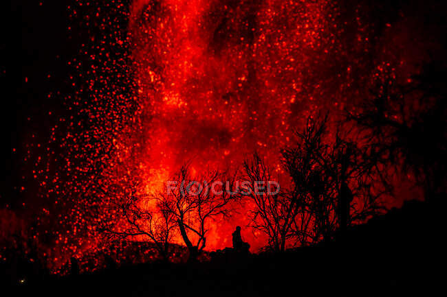 Silhouette humaine assise contre l'explosion de lave et de magma coulant du cratère. Éruption volcanique Cumbre Vieja à La Palma Îles Canaries, Espagne, 2021 — Photo de stock