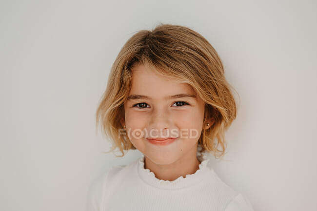 Дружелюбный симпатичный ребенок с каштановыми волосами, смотрящий в камеру — стоковое фото