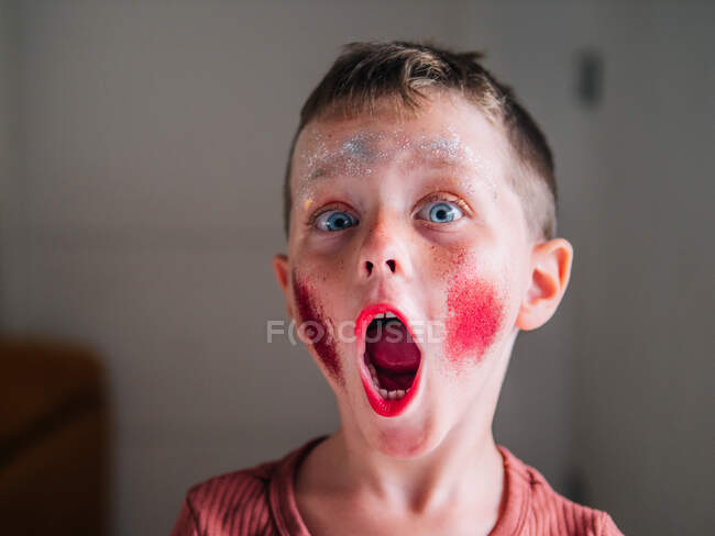 Bambino stupito con la faccia sporca con la bocca mentre guarda la fotocamera a casa — Foto stock