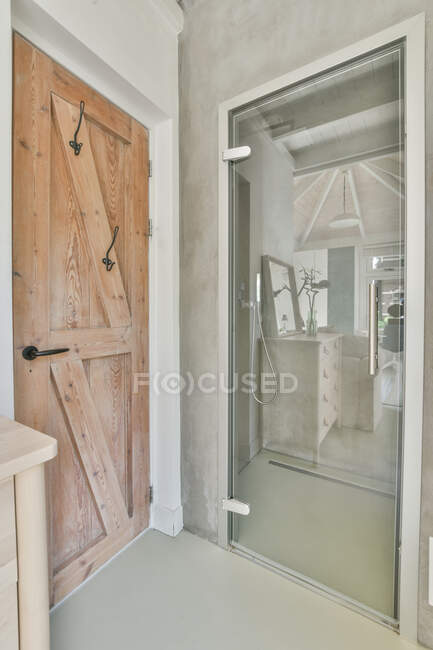 Інтер'єр кімнати з дерев'яними і скляними дверима в квартирі з сірими стінами — стокове фото