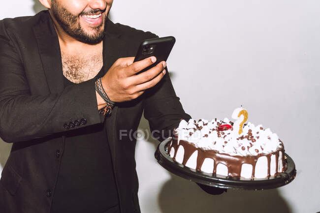 Crop cheerful male with mouth opened taking picture of delicious birthday cake during party — Stock Photo