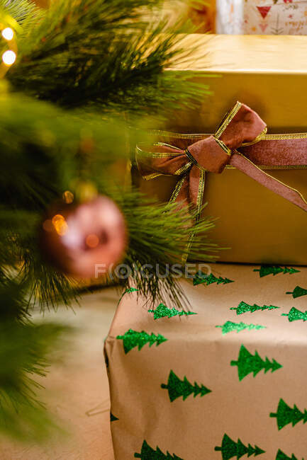 Коллекция рождественских подарков, завернутых в бумагу и ленты, помещенных возле ветвей елки — стоковое фото