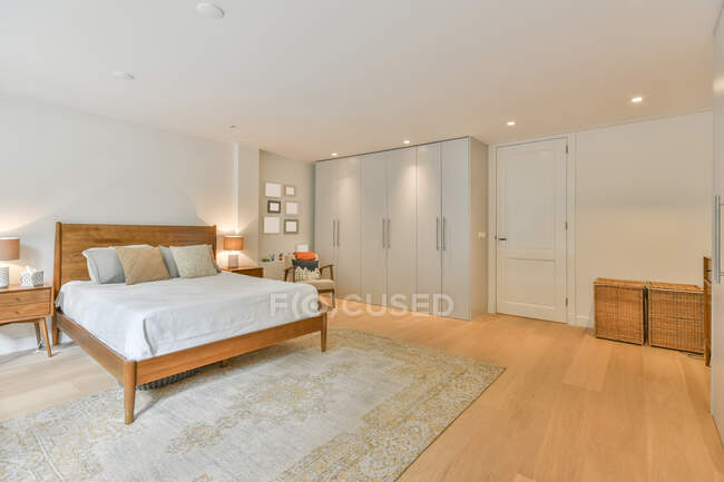 Interior de dormitorio moderno con cama cómoda y armario grande en apartamento nuevo - foto de stock