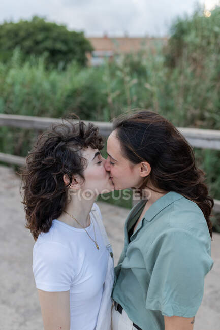 Desde arriba de la mujer joven de moda con homosexual amado besos en el puente - foto de stock