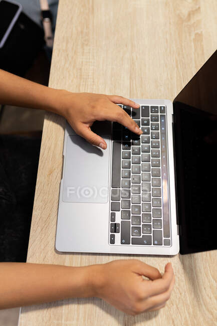 Von oben beschnitten unkenntlich junge Unternehmerin sitzt am Tisch und blättert Netbook während der Arbeit an modernen Arbeitsplatz — Stockfoto