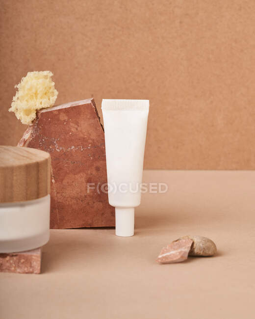 Handmade soap bar with sponge against tube and jar of cream with eco lid on two color background — Stock Photo