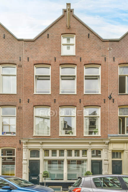 Extérieur du vieux bâtiment résidentiel avec des murs de briques et des fenêtres sous le ciel bleu de la ville — Photo de stock