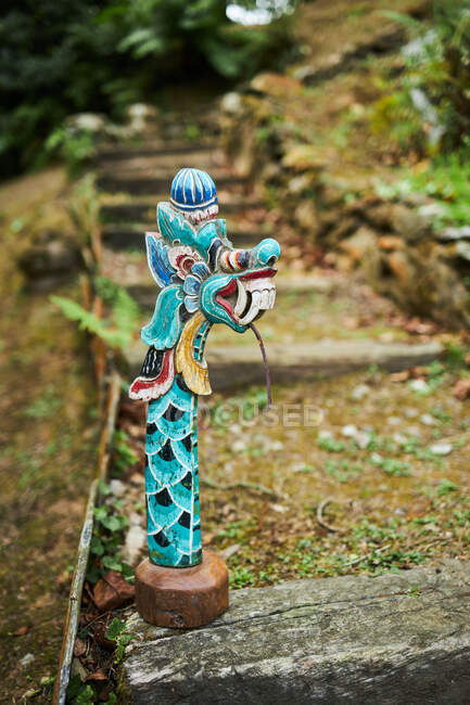 Sculpture of dragon with ornament on staircase against rough stone lantern in garden of Bali Indonesia — Stock Photo