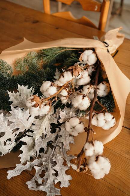 Festlicher Weihnachtsstrauß mit Zweigen aus Baumwolle und Tanne auf Holztisch im Zimmer — Stockfoto