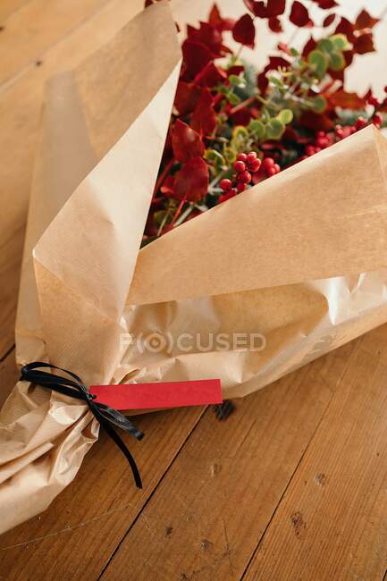 Dall'alto di bouquet di Natale decorativo elegante festivo con ramoscelli di eucalipto e rami rossi lucenti con bacche messe su tavolo di legno in camera — Foto stock