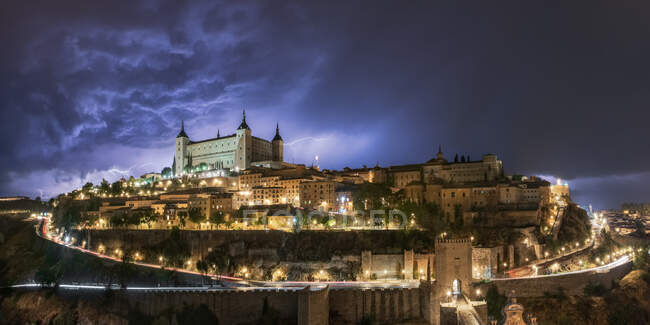 Cityscape with aged famous castle Alcazar of Toledo placed in Spain under cloudy sky in night time during thunderstorm — Stock Photo