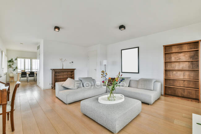 Interior de la habitación contemporánea con sofás y mesa contra ventanas casa a la luz del día - foto de stock
